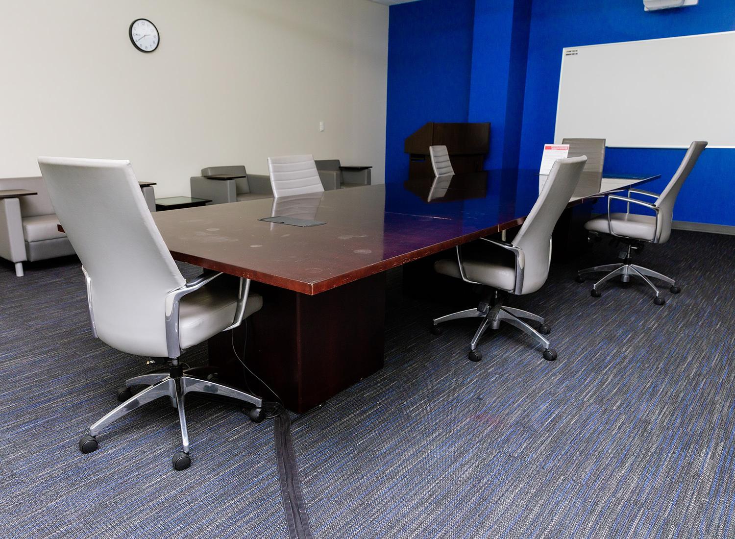105号会议室，向右展示一张会议桌和椅子, 一个讲台, 还有一块白板
