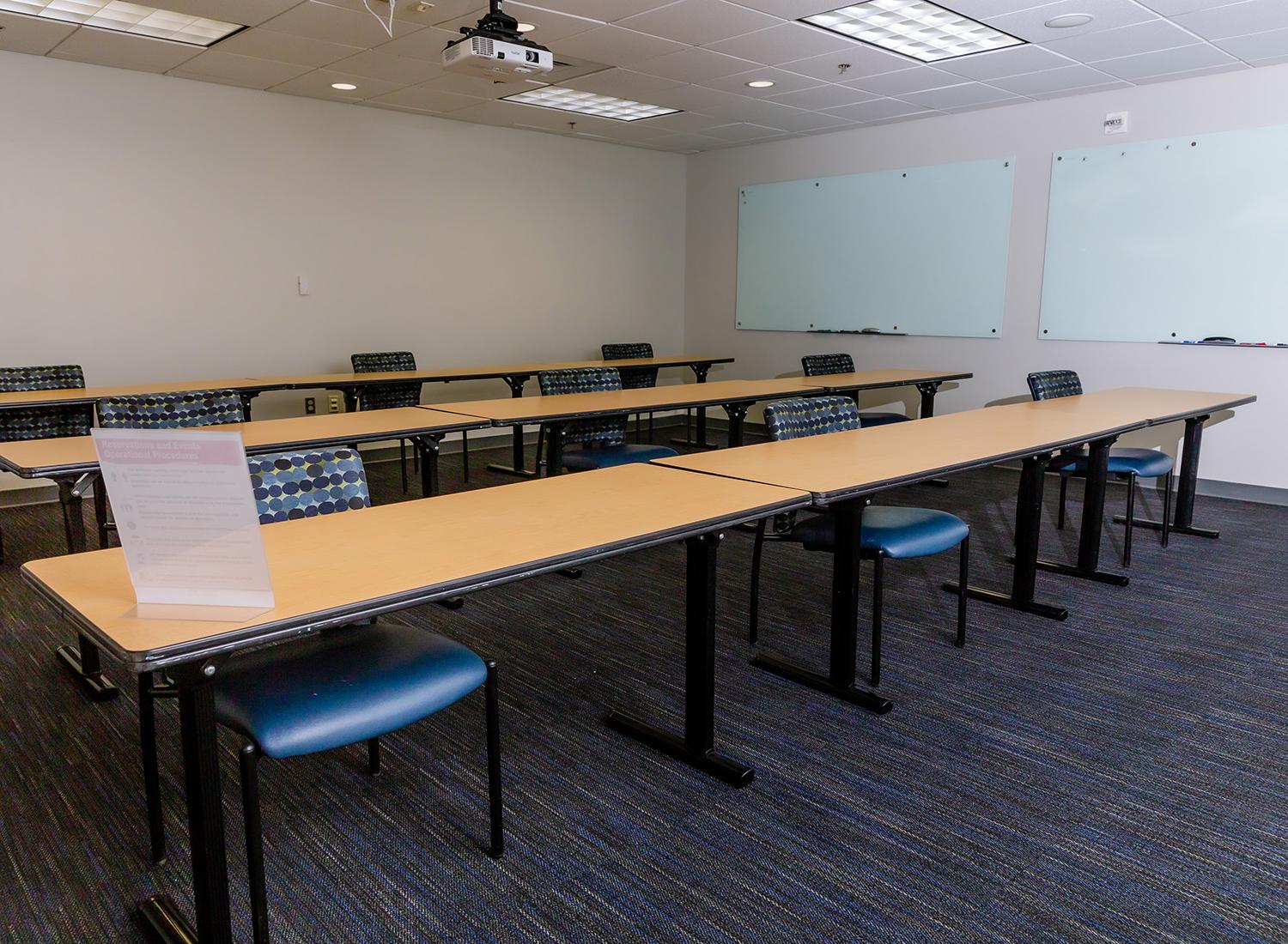 302会议室面向房间的后面，展示了长桌子和间隔座位以及两块白板